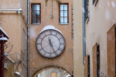 Lviv, Ukrayna - 24 Ocak 2026: Yoğun bir kar yağışı sırasında Lviv avlusunda, kemerin üzerinde antik yuvarlak bir saat.