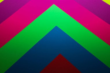 Canlı renkli kağıt katmanlarının soyut geometrik bileşimi dinamik bir ok ya da sembol deseni oluşturur. Mavinin, yeşilin, pembenin ve kırmızının zengin tonlarına sahip minimalist arka plan modern grafik tasarım ve yaratıcı projeler için mükemmeldir..