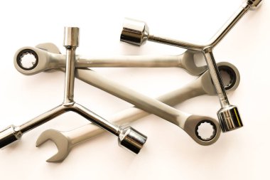 Çeşitli çelik anahtarlar ve prizler rastgele hafif bir yüzeye dağılır ve profesyonel bir çalışma bileşimi oluşturur..