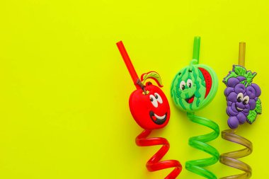 Lviv, Ukrayna - 25 Şubat 2026: Parlak spiral içme pipetleri bir elma, karpuz ve gülen yüzlü üzümlerle süslenmiştir.