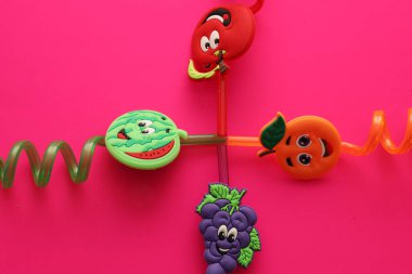 Lviv, Ukrayna - 25 Şubat 2026: Komik kauçuk meyveli dört parlak çubuk elma, karpuz, portakal ve üzüm haç şeklinde serilmiştir.