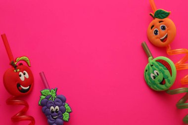 Lviv, Ukrayna - 25 Şubat 2026: Karikatür meyveli neşeli kıvırcık pipetler parlak pembe bir arka planın kenarlarına yerleştirilir ve festival içeriği için mükemmel bir çerçeve oluşturulur.