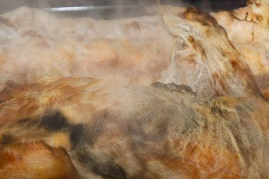 Gazlı beze sarılı sıcak füme et pişirdikten hemen sonra yoğun buhar salar. İştah açıcı altın kabuk ve kumaşın dokusu ev yapımı işleme metodunu vurguluyor ve özgün bir tarım lezzeti atmosferi yaratıyor..