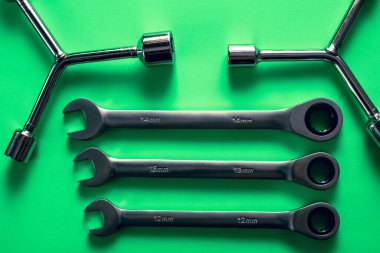 Üç cırcırlı anahtar ve iki üçlü soket anahtarı parlak yeşil arka planda güzelce yerleştirilmiş. Metrik boyutlarda profesyonel krom araçlar, verimli teknik bakım, araba tamiri ve montaj sağlar.