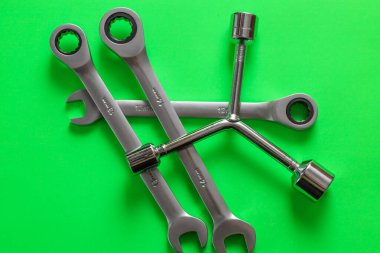 Bir takım çelik anahtarlar ve Y şeklindeki soket anahtarı parlak yeşil bir arka plana rastgele saçılmış..
