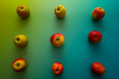 Dokuz kırmızı ve sarı elma canlı yeşil-mavi gradyan arkaplan üzerinde 3x3 ızgarada eşit olarak sıralanır..