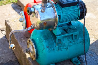 Açık havada beton bir üsse bir turkuaz otomatik pompalama istasyonu kuruluyor. Yüzey pompası ve hidrolik akümülatörü olan ekipmanlar özerk su tedariği ve özel ev sisteminde basıncı korumak için tasarlanmıştır..