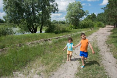 Güzel küçük erkek ve kız yol parlak güneşli bir çam ormanı bulunmaktadır.
