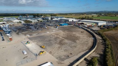 An aerial view of a large industrial site featuring warehouses, parked vehicles, construction equipment, and undeveloped land  at Copart yard, York, UK.
