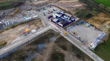 Taylor Wimpey, Ripon 'da ağır makineler, araçlar, binalar ve istiflenmiş malzemelerle dolu bir inşaat alanının havadan görüntüsü..