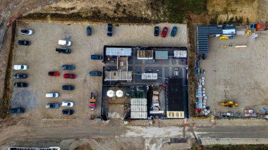 Modüler binaların, park edilmiş araçların ve inşaat malzemelerinin bulunduğu bir inşaat alanının havadan görünüşü, Taylor Wimpey, Ripon 'da toprak ve çakıl zeminine karşı..