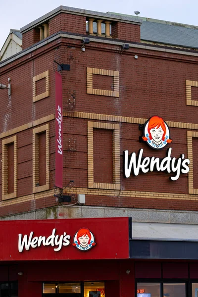 Kırmızı tuğlalı bir binada Wendy 'nin açık renkli tuğla aksanları ve İngiltere' nin Blackpool şehrinde açık bir gökyüzü bulunan birden fazla restoran tabelaları ve pankartları yer alıyor..