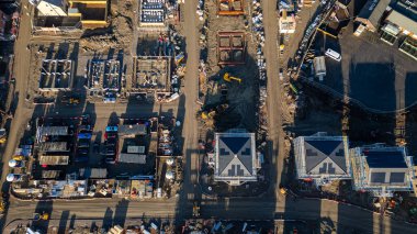 İnşaat halindeki binaların, ağır makinelerin, araçların ve inşaat malzemelerinin bulunduğu bir inşaat alanının havadan görüntüsü..