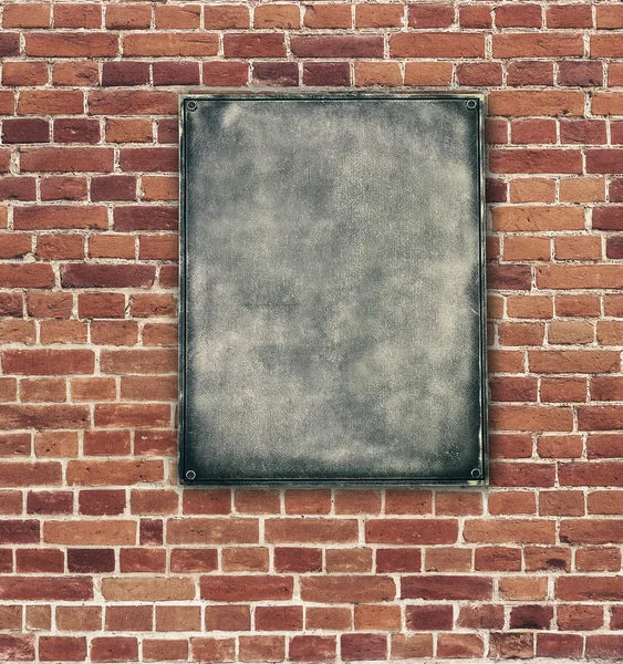 Kırmızı tuğla duvar arka plan üzerinde eski metal plaka