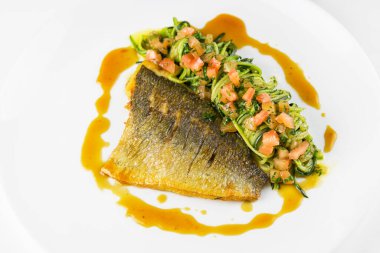 Dorado balıklı fileto, sebzeli ve beyaz tabakta.