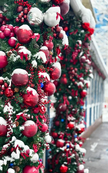 Yılbaşı süslemeleri kırmızı mücevherler ve binanın ön cephesinde kar.