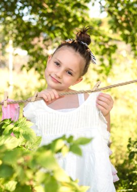Bahçedeki bir ipe çamaşırlarını asan küçük bir kızın portresi. Eski çamaşır yıkama, eko konsepti