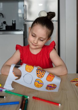 Genç liseli kız evde mutfakta paskalya süsleri ve yumurta çiziyor. Paskalya için dekoru kız kendisi çiziyor ve oyuyor..