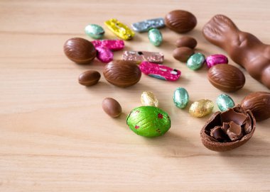 Ahşap arka planda renkli çikolatalı Paskalya yumurtaları. Yakın plan.