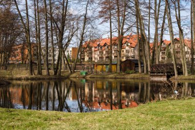 Güzel bir bahar manzarası, çok katlı güzel bir bina manzarası. Bir göl, ağaçlı bir park ve kırmızı çatılı bir ev..