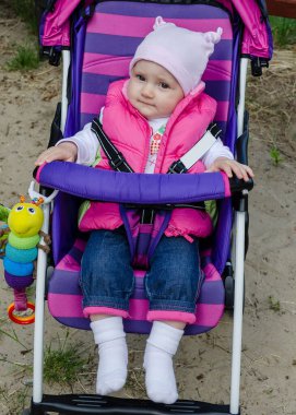 Bebek arabasındaki bebek portresi. Pembe ve mor çizgili bebek arabasında