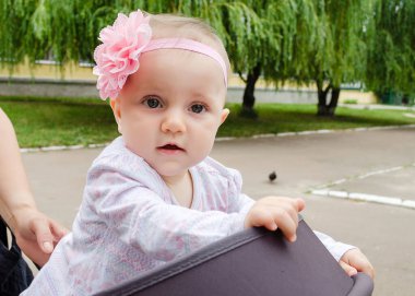 Yavru 9 aylık ve baharda sokakta başında büyük pembe bir çiçek var..