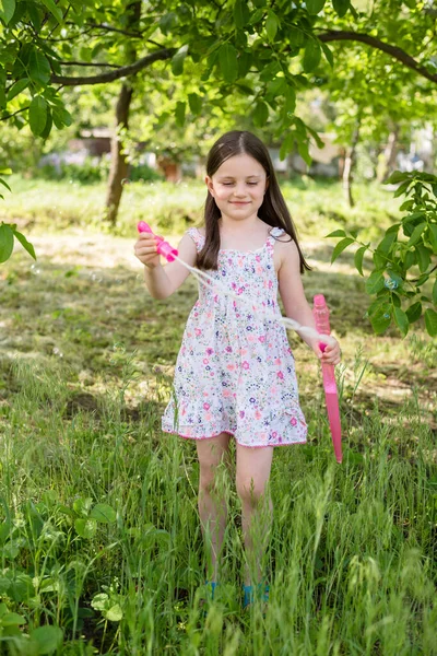 Little girl makes soap bubbles in the summer in the garden
