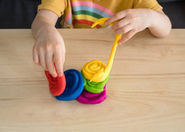 Çocuk elleri renkli kille oynuyor. Ev yapımı plastik. Karantinadaki çocuklar için etkinlikler. İzolasyon yüzünden evde plastik heykeller yapan bir kız. Coronavirus 2021.