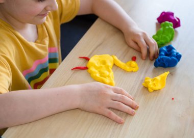 Anaokulundan bir kız plastik ördekten ördek yapıyor. Ev yapımı plastik. Karantinadaki çocuklar için etkinlikler. İzolasyon yüzünden evde plastik heykeller yapan bir kız. Coronavirus 2021.