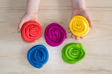 Çocuk elleri renkli kille oynuyor. Ev yapımı plastik. Karantinadaki çocuklar için etkinlikler. İzolasyon yüzünden evde plastik heykeller yapan bir kız. Coronavirus 2021.
