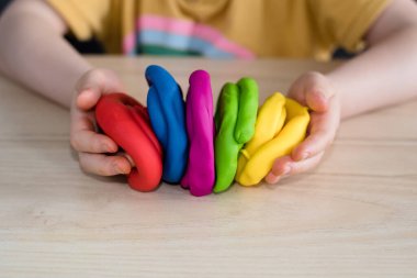 Çocuk elleri renkli kille oynuyor. Ev yapımı plastik. Karantinadaki çocuklar için etkinlikler. İzolasyon yüzünden evde plastik heykeller yapan bir kız. Coronavirus 2021.