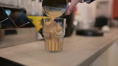 Barmen buzlu bir bardağa kahve dolduruyor.