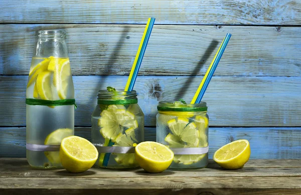 Limonada fría en botellas con limones —  Fotos de Stock