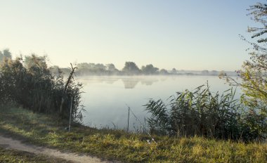 Puslu gündoğumu yaz sabahı bir göl üzerinde