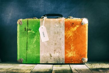 Tahta arka planda İrlanda bayrağı olan eski bavul. Seyahat