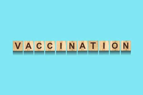 Vaccinatie belettering op houten blokken, op een blauwe achtergrond. Coronavirusvaccin. COVID-19. Geïsoleerd. Virusbescherming. — Stockfoto