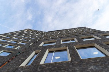 Bulutlu bir gökyüzünün arka planına karşı güzel bir tuğla binanın ön cephesi. Alt manzara. Mimari.