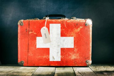 Tahta arka planda İsviçre bayrağı olan eski bavul. Seyahat