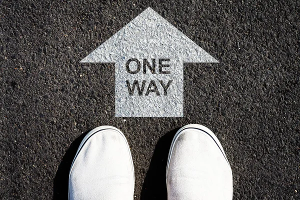 Tek yön. Başarı. Doğru yönde. Yoldaki beyaz ok ve spor ayakkabılar. Yukarıdan bak. İş dünyası.