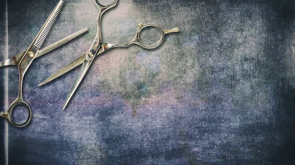 Hairdressing scissors on a dark, shabby grunge background. Copy space. Beauty and fashion.