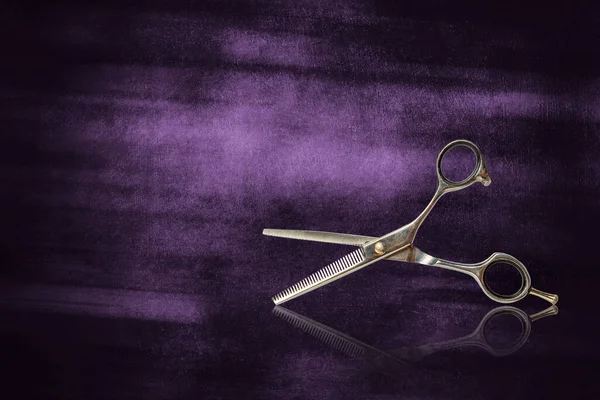 Vintage, old, hairdressing scissors, on shabby purple background. Barbershop background. Reflection. Copy space.