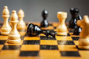 Siyah papaz satranç tahtasında yatıyor. Seçici odaklanma. Yenilgi. Kötü strateji konsepti. Spor. İş dünyası.