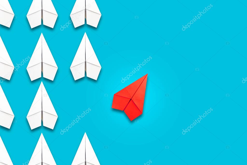 Red paper plane flying in a different direction than the white ones. Blue background. Copy space. The concept of innovative solutions, creativity. Business. Lifestyle. Background.