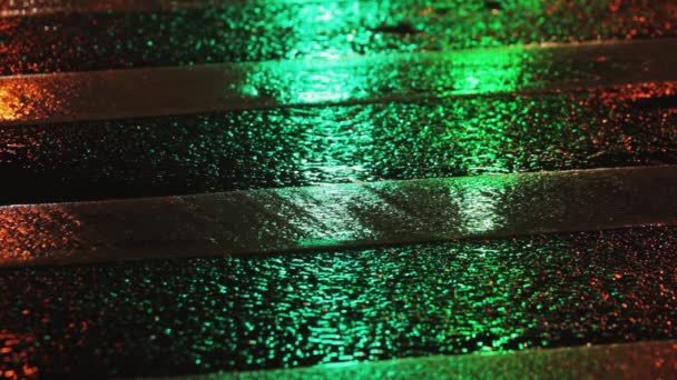 Regenachtige avond in de stad. Weerspiegeling van verkeerslichten verandert van rood naar groen — Stockvideo