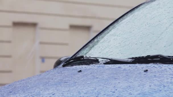 Raindrops and snowflakes on automobile windshield and car body . — Stock Video