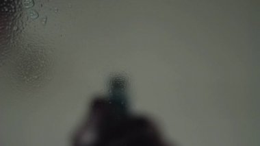 Cam kameraya el sprey sıvı. Cam üzerindeki aşağı damla akış