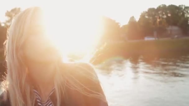 Jeune fille posant sur l'herbe verte près de la rivière au coucher du soleil — Video