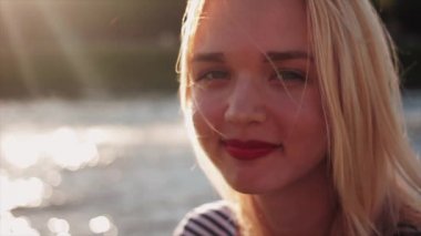 Genç kadın kameraya bakıyor ve gülümsüyor.