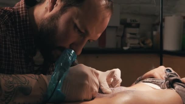 Maestro del tatuaje con barba haciendo un tatuaje de patrón de mandala. Primer plano. — Vídeos de Stock
