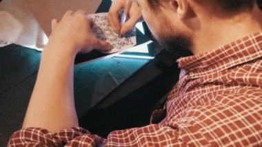 Bükümleri gömlekli sakallı adam mandala geometrik desen bir lightbox kopya kağıdı kullanarak çizer.